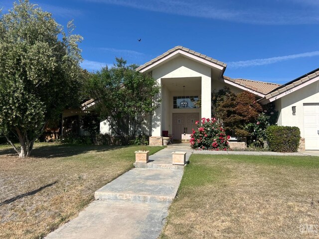 view of front of house featuring stucco siding, a tiled roof, and a front yard