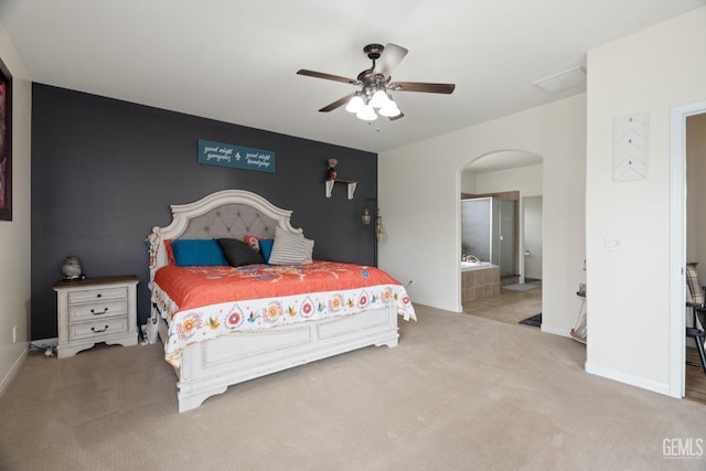 bedroom with arched walkways, ceiling fan, light carpet, an accent wall, and baseboards