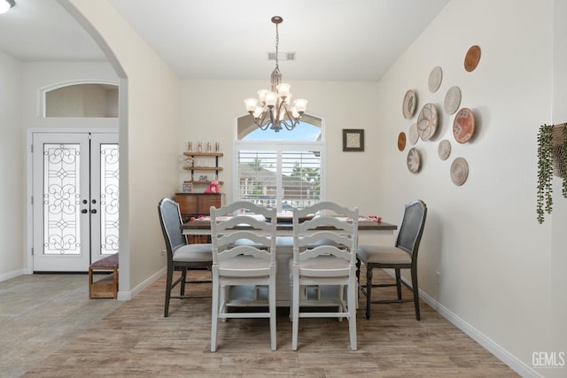 dining area with baseboards, visible vents, a chandelier, and arched walkways