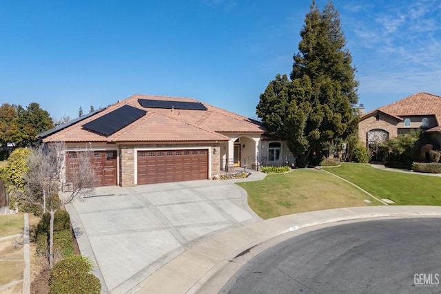 view of front of property with a garage, a tile roof, driveway, roof mounted solar panels, and a front lawn