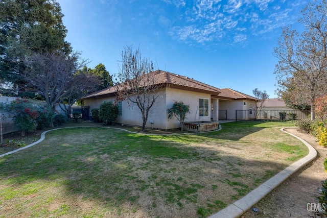 exterior space featuring a tiled roof, a lawn, a fenced backyard, and stucco siding