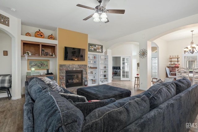 living area featuring a fireplace, built in features, arched walkways, and wood finished floors