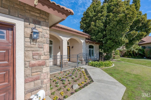 property entrance featuring a tile roof, a yard, stucco siding, a garage, and stone siding