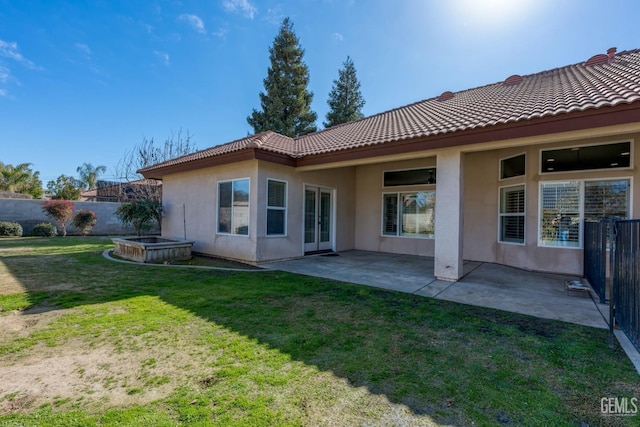 back of house featuring a patio, a fenced backyard, a yard, a tiled roof, and stucco siding