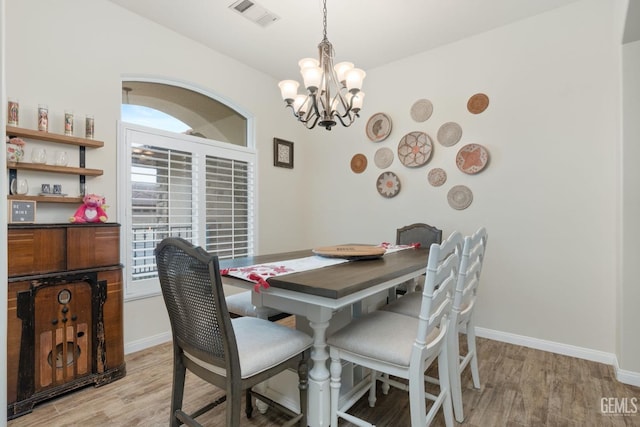 dining space featuring a chandelier, light wood-style flooring, visible vents, and baseboards