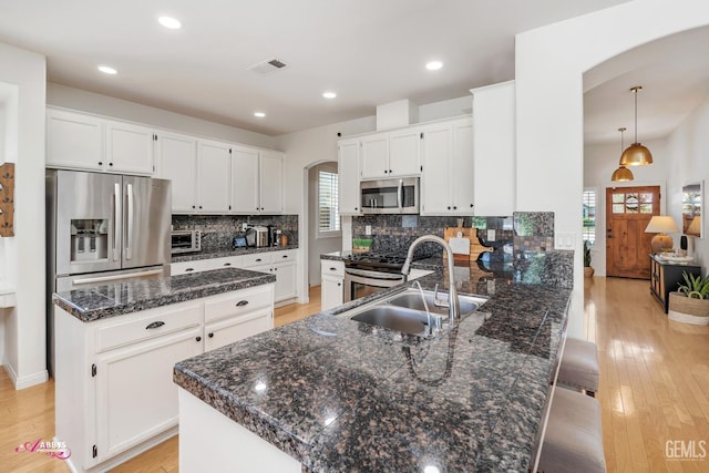 11820 Crescent Creek Ct, Bakersfield, CA 93311 - kitchen featuring stainless steel appliances, arched walkways, a peninsula, backsplash, and light wood-style floors