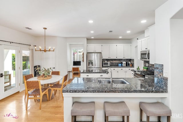 11820 Crescent Creek Ct, Bakersfield, CA 93311 - kitchen with appliances with stainless steel finishes, a chandelier, a peninsula, backsplash, and light wood-type flooring
