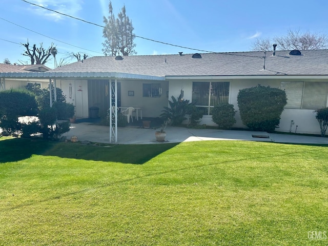 back of property featuring a patio area, a shingled roof, a lawn, and stucco siding