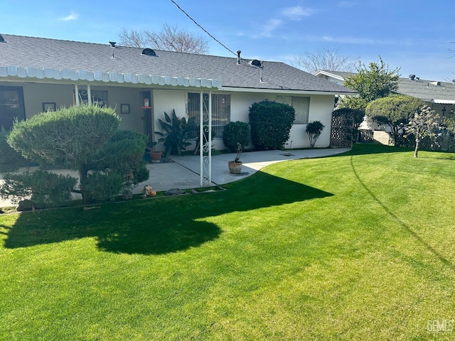 rear view of house with a yard, a patio, and stucco siding