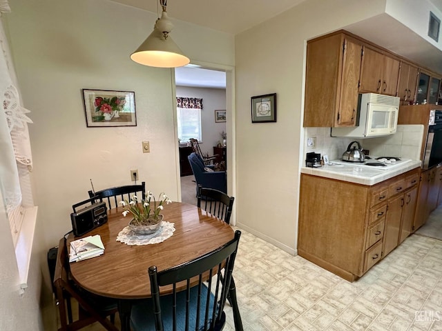 kitchen with tile countertops, white appliances, brown cabinets, light floors, and tasteful backsplash