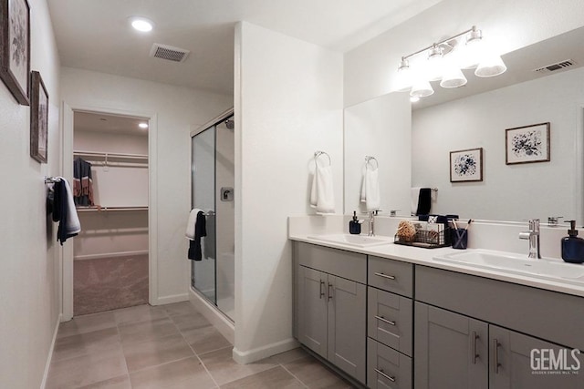 bathroom with a shower with door, tile patterned flooring, and vanity