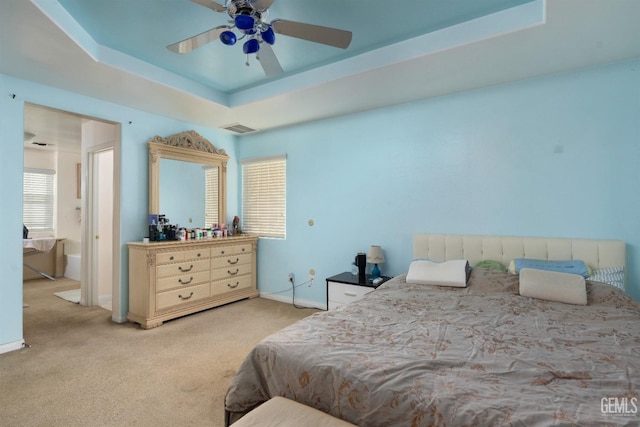 bedroom featuring multiple windows, light colored carpet, ceiling fan, and a raised ceiling