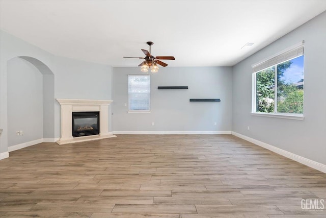 11311 Mezzadro Ave, Bakersfield, CA 93312 - unfurnished living room with wood finished floors, ceiling fan, a glass covered fireplace, and arched walkways