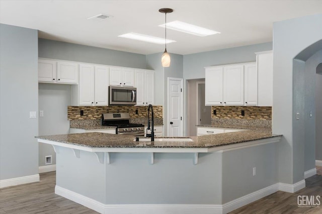 11311 Mezzadro Ave, Bakersfield, CA 93312 - kitchen featuring stainless steel appliances, tasteful backsplash, light wood-type flooring, dark stone countertops, and arched walkways