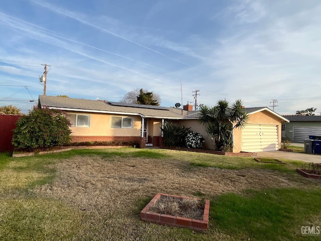 ranch-style home with a garage, a front lawn, and solar panels