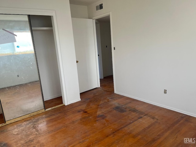 unfurnished bedroom featuring dark wood-type flooring and a closet