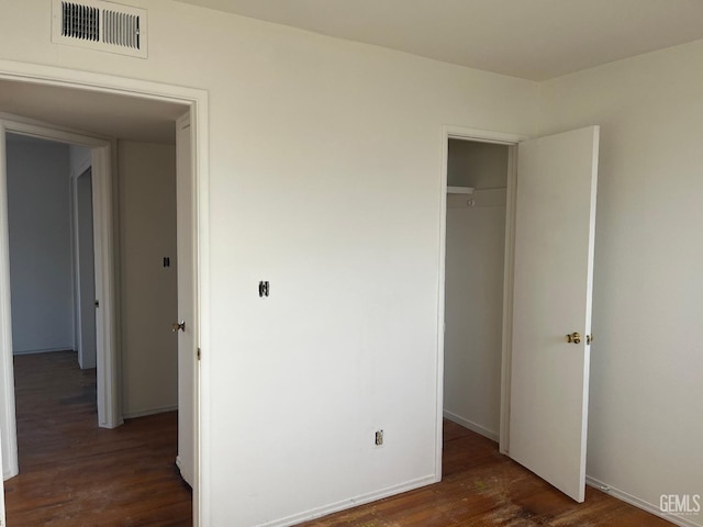 unfurnished bedroom featuring dark hardwood / wood-style flooring and a closet