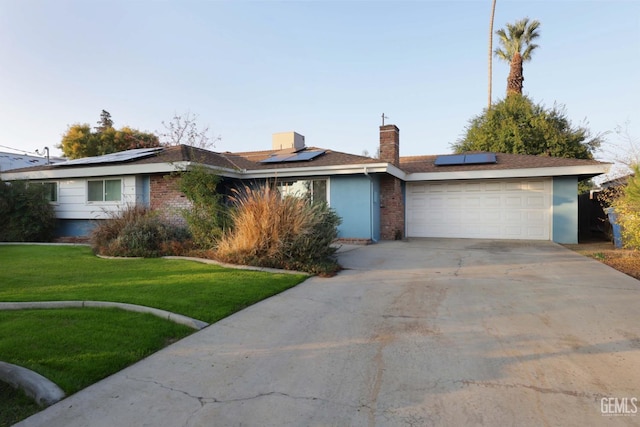 ranch-style house with solar panels, a front yard, and a garage