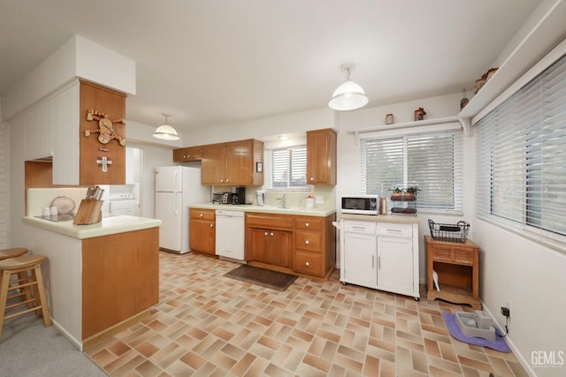 kitchen with sink, white appliances, and hanging light fixtures