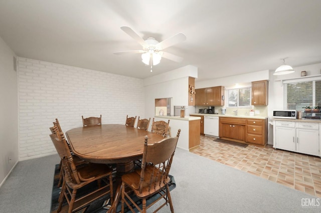 carpeted dining room featuring ceiling fan and brick wall