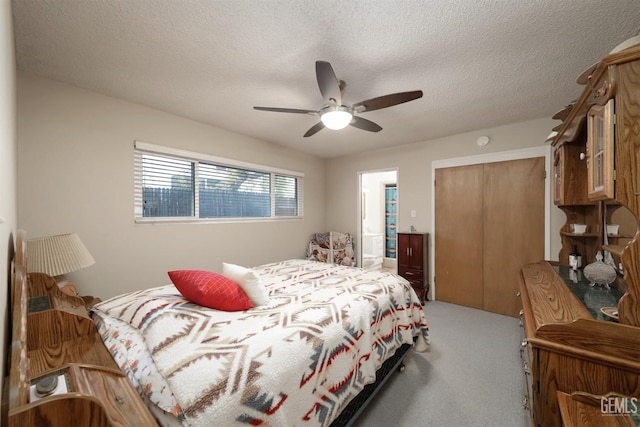 carpeted bedroom with a textured ceiling, a closet, ensuite bath, and ceiling fan