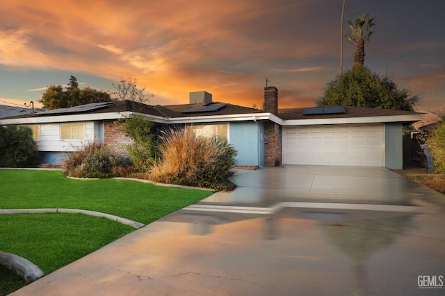 view of front of house featuring solar panels, a yard, and a garage