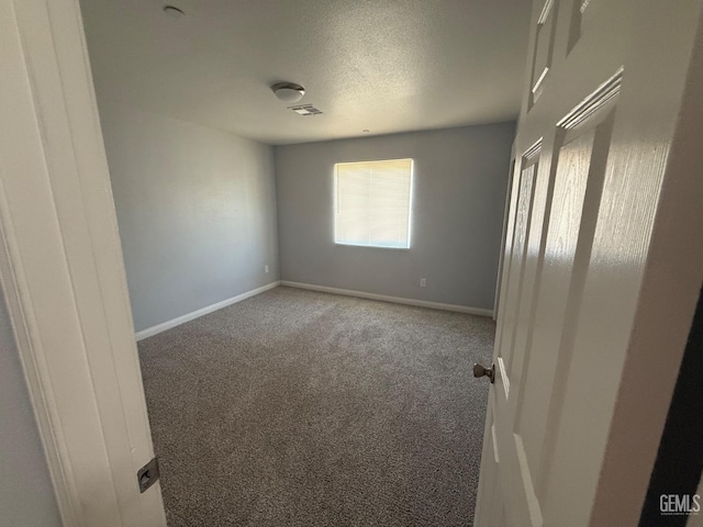 spare room featuring carpet floors and a textured ceiling