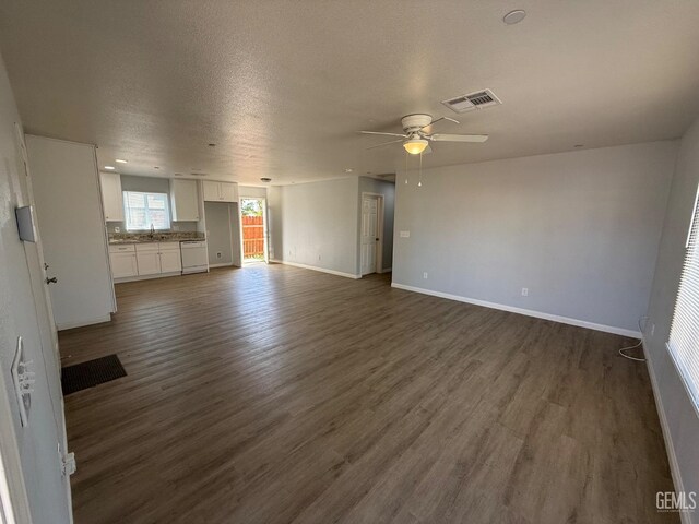 unfurnished living room featuring ceiling fan, dark wood-type flooring, sink, and a textured ceiling