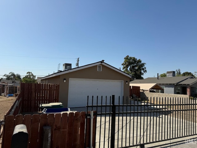 view of front of home featuring a garage, central AC unit, and an outdoor structure