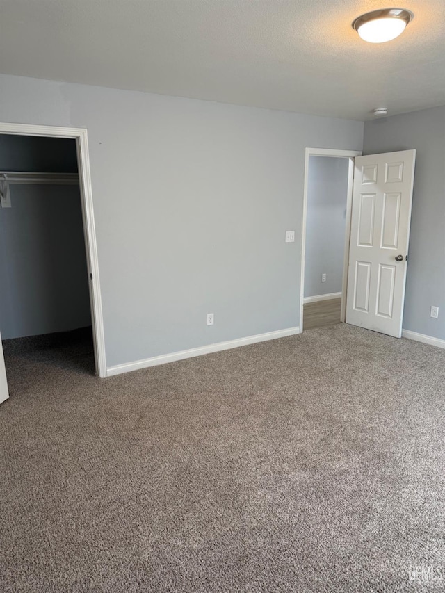 unfurnished bedroom featuring a walk in closet, a closet, and carpet flooring