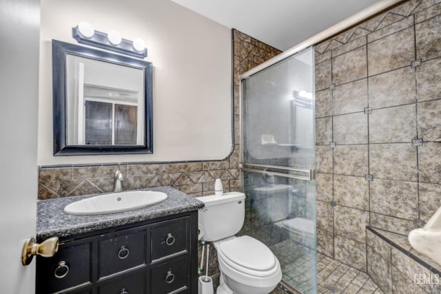 bathroom with an enclosed shower, vanity, toilet, and tile walls