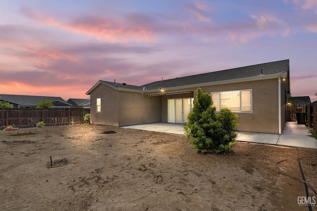 6622 Sycamore Wood Ln, Bakersfield, CA 93313 - back of property at dusk featuring a patio area, a fenced backyard, and stucco siding