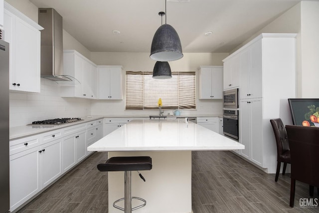6622 Sycamore Wood Ln, Bakersfield, CA 93313 - kitchen with appliances with stainless steel finishes, wall chimney exhaust hood, wood finish floors, a kitchen bar, and white cabinets
