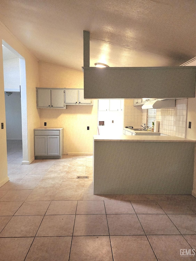 200 5th Ave Unit 32, Arvin, CA 93203 - kitchen featuring gray cabinets, decorative backsplash, a peninsula, baseboards, and light tile patterned floors