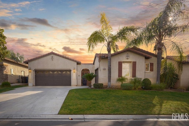 mediterranean / spanish-style house with a garage and a yard