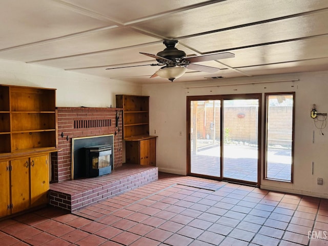 unfurnished living room with tile patterned flooring, ceiling fan, and a wood stove