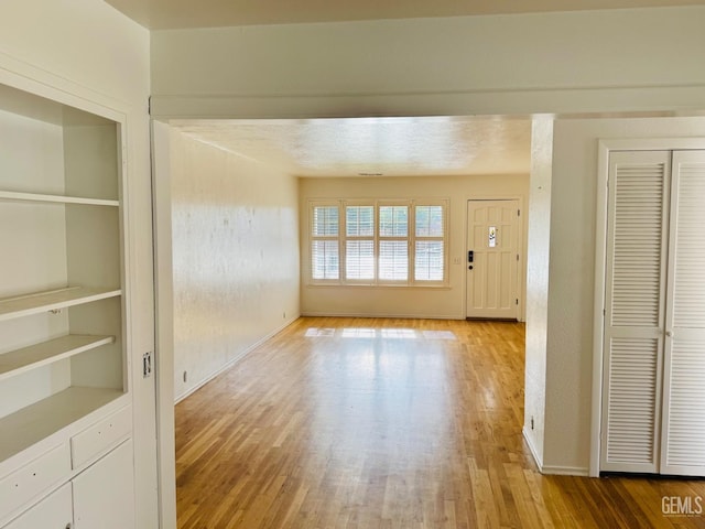 unfurnished living room featuring light wood-type flooring and built in features