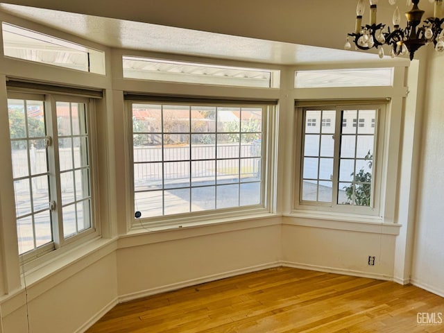 unfurnished dining area with a notable chandelier and light wood-type flooring