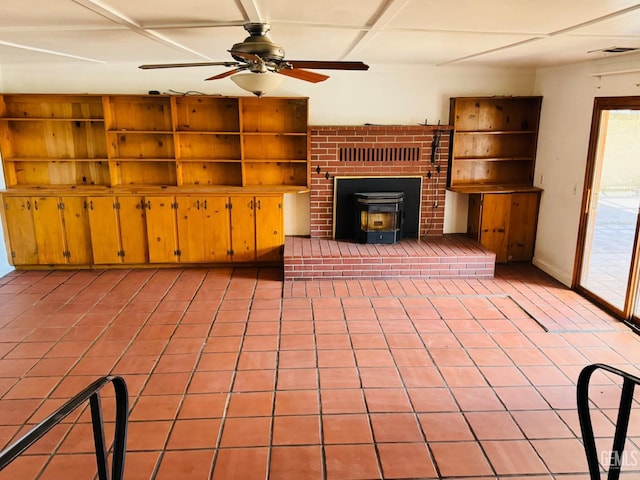 unfurnished living room featuring a wood stove, ceiling fan, and light tile patterned floors