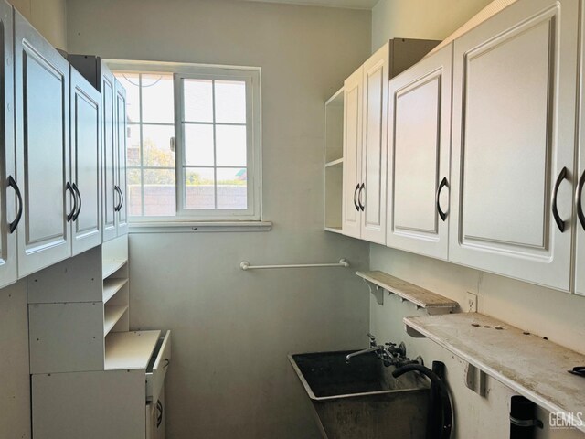 laundry area with cabinets and sink