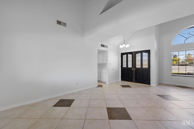 foyer featuring visible vents, baseboards, a notable chandelier, and a towering ceiling