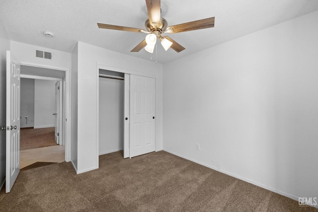 unfurnished bedroom featuring visible vents, carpet floors, a closet, a textured ceiling, and a ceiling fan