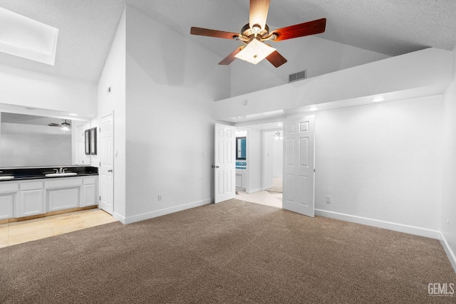 unfurnished bedroom featuring visible vents, light carpet, a sink, a skylight, and baseboards