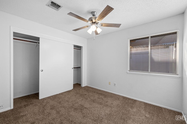 unfurnished bedroom with visible vents, a textured ceiling, a closet, carpet floors, and baseboards