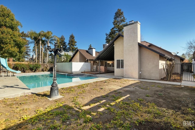 view of swimming pool featuring a patio area, a pool with connected hot tub, a water slide, and a fenced backyard