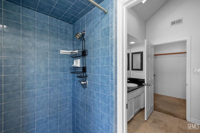 full bath featuring tile patterned flooring, visible vents, tiled shower, and vanity