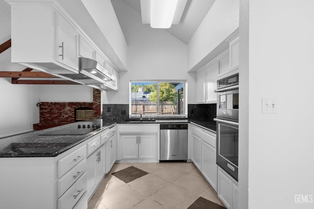 kitchen with tasteful backsplash, vaulted ceiling, appliances with stainless steel finishes, white cabinets, and a sink