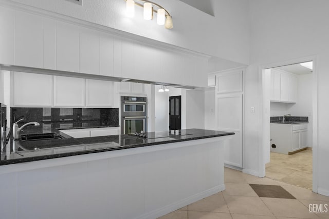 kitchen with white cabinets, double oven, black electric cooktop, and a sink