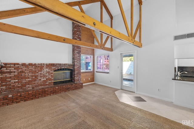 unfurnished living room with visible vents, a brick fireplace, baseboards, beam ceiling, and carpet flooring