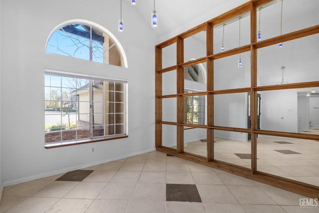 spare room featuring baseboards, high vaulted ceiling, and tile patterned flooring